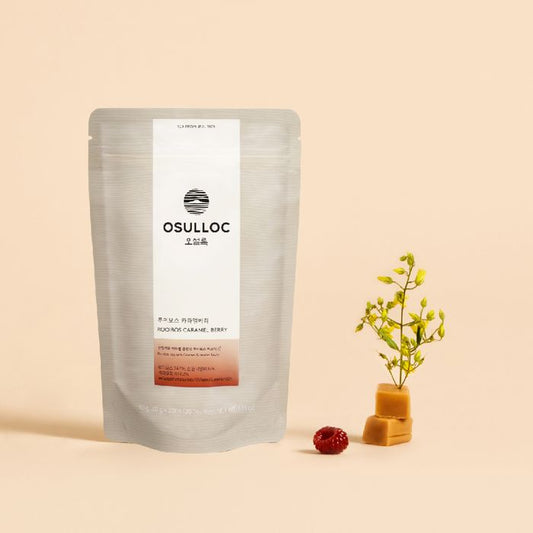 Boîte de Rooibos Caramel Berry OSULLOC beige avec une tasse d'infusion ambrée et des baies rouges.