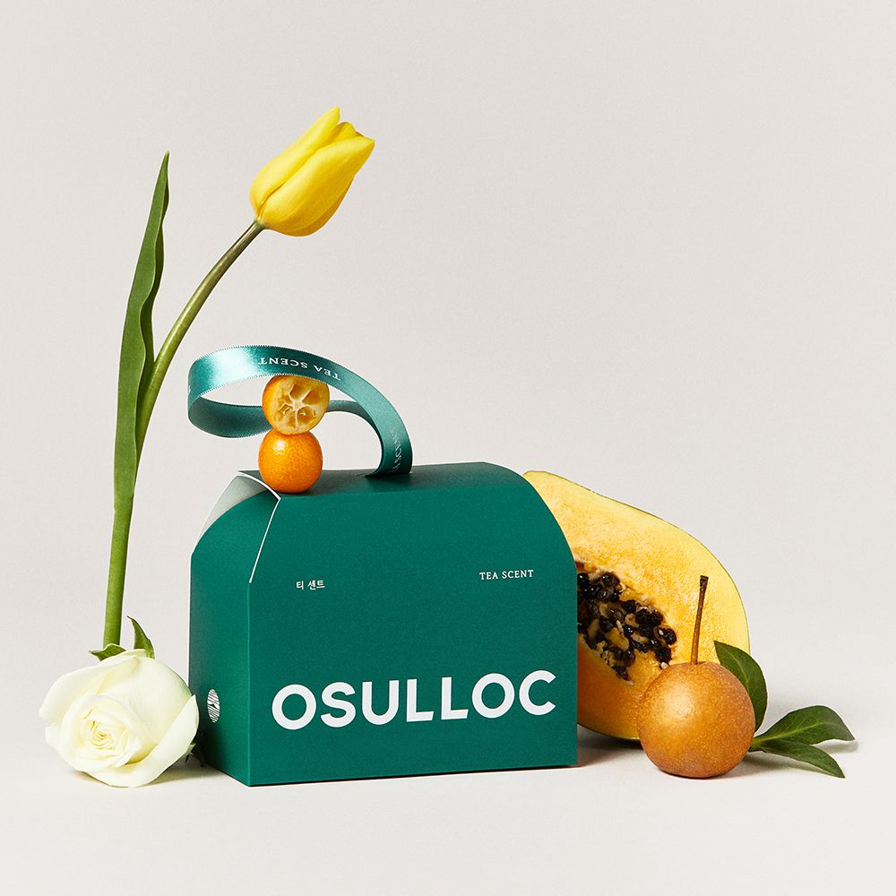 Coffret vert OSULLOC 24 sachets avec poignée, entouré d'une tulipe jaune et de fruits tropicaux.