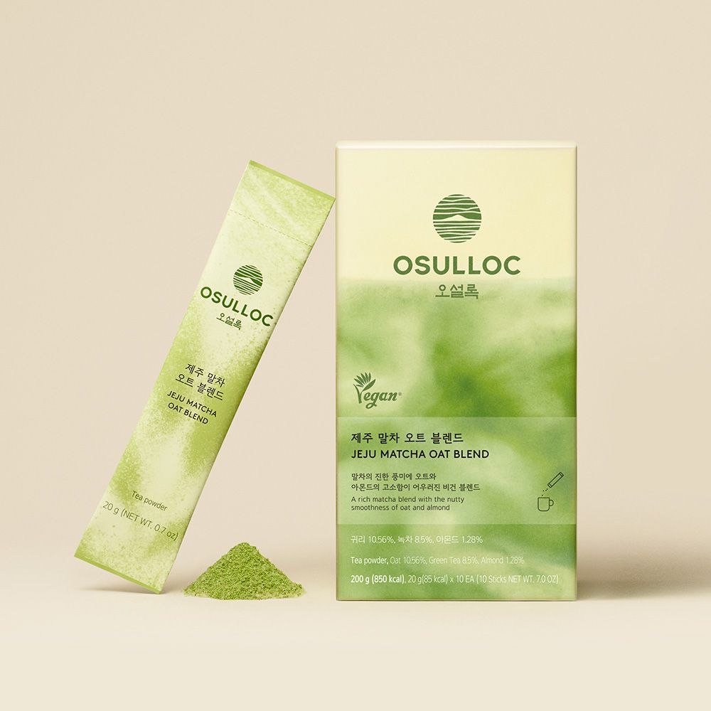 Boîte verte OSULLOC Jeju Matcha Oat Blend et un stick de matcha à l'avoine posé avec de la poudre de matcha
