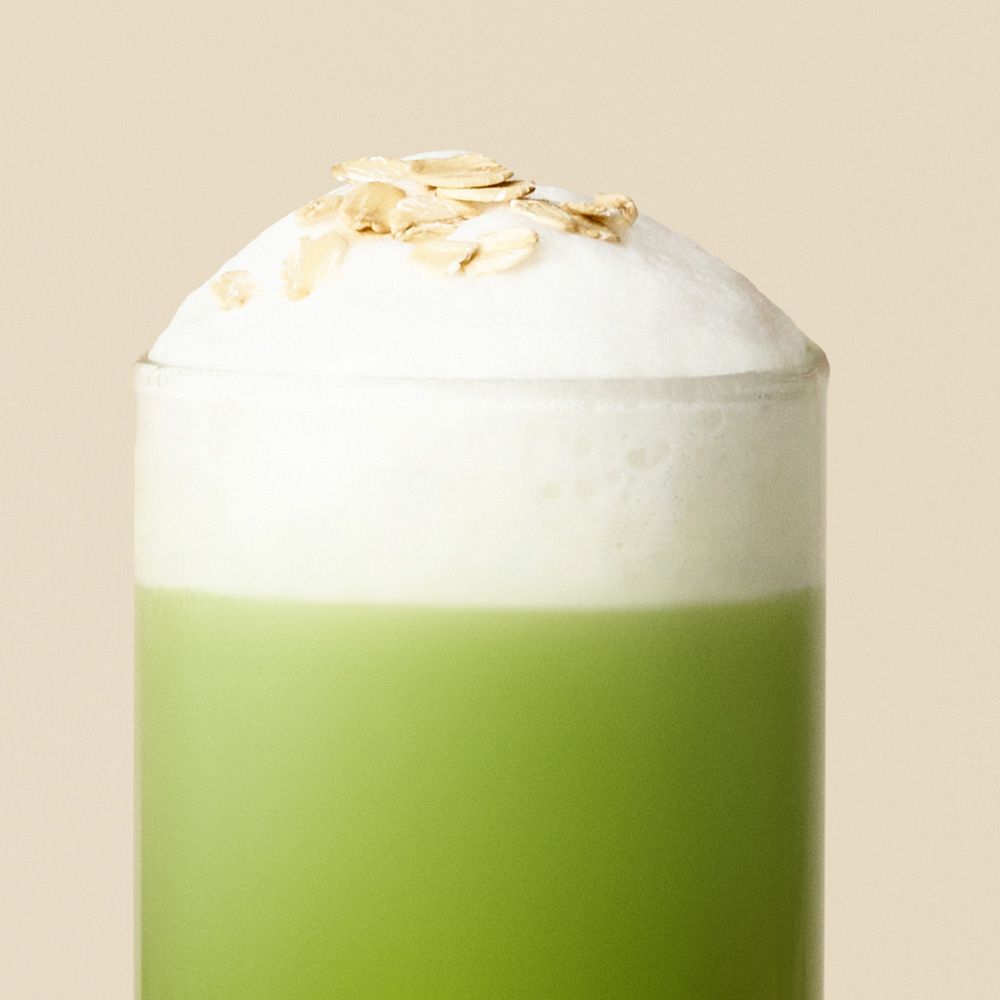 Verre de latte matcha à l'avoine avec mousse onctueuse et flocons d'avoine