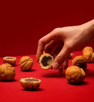 une main prend une des Pâtisseries Traditionnelles "Hodu-Gwaja" aux Noix