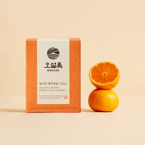 Boîte orange OSULLOC Samdayeon Jeju Tangerine posée à côté de deux mandarines fraîches sur un fond beige doux.
