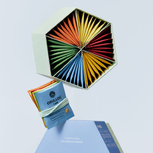 Coffret bleu et vert hexagonal OSULLOC Tea Variation Essence ouvert révélant 42 sachets de thé multicolores.