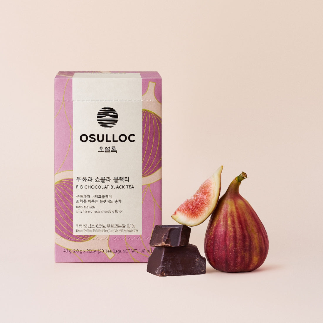 Boîte de thé OSULLOC Fig Chocolate sur un fond d'herbe avec des figues fraîches coupées et des fèves de cacao.