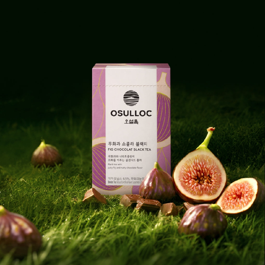 Boîte de thé OSULLOC Fig Chocolate sur un fond d'herbe avec des figues fraîches coupées et des fèves de cacao.