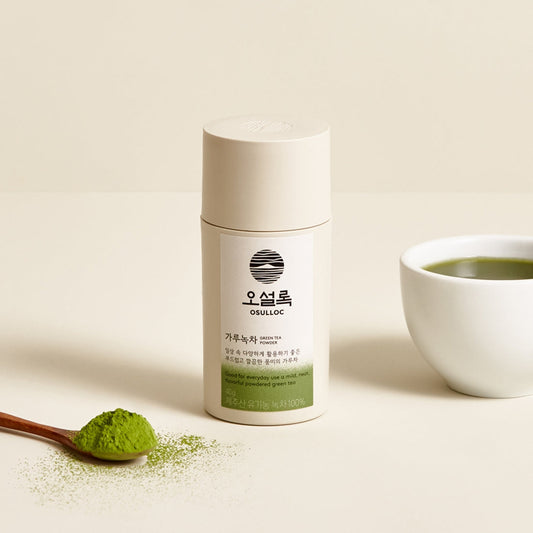 Flacon blanc de poudre de OSULLOC Green Tea Powder bio 40g avec une cuillère en bois contenant du matcha et une tasse de thé à côt