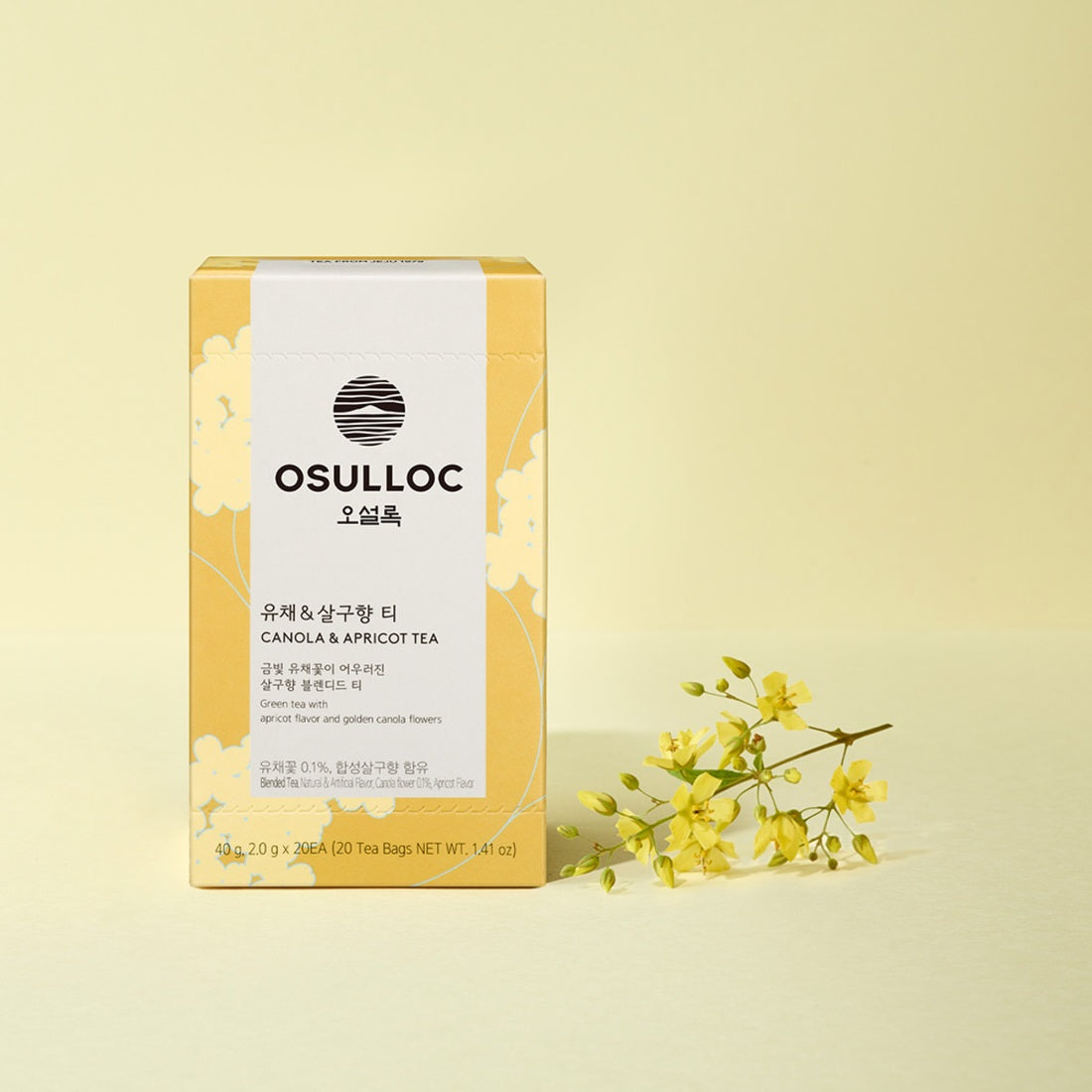 Boîte jaune OSULLOC Canola & Apricot Tea avec une tasse de thé claire et des fleurs de colza jaunes.