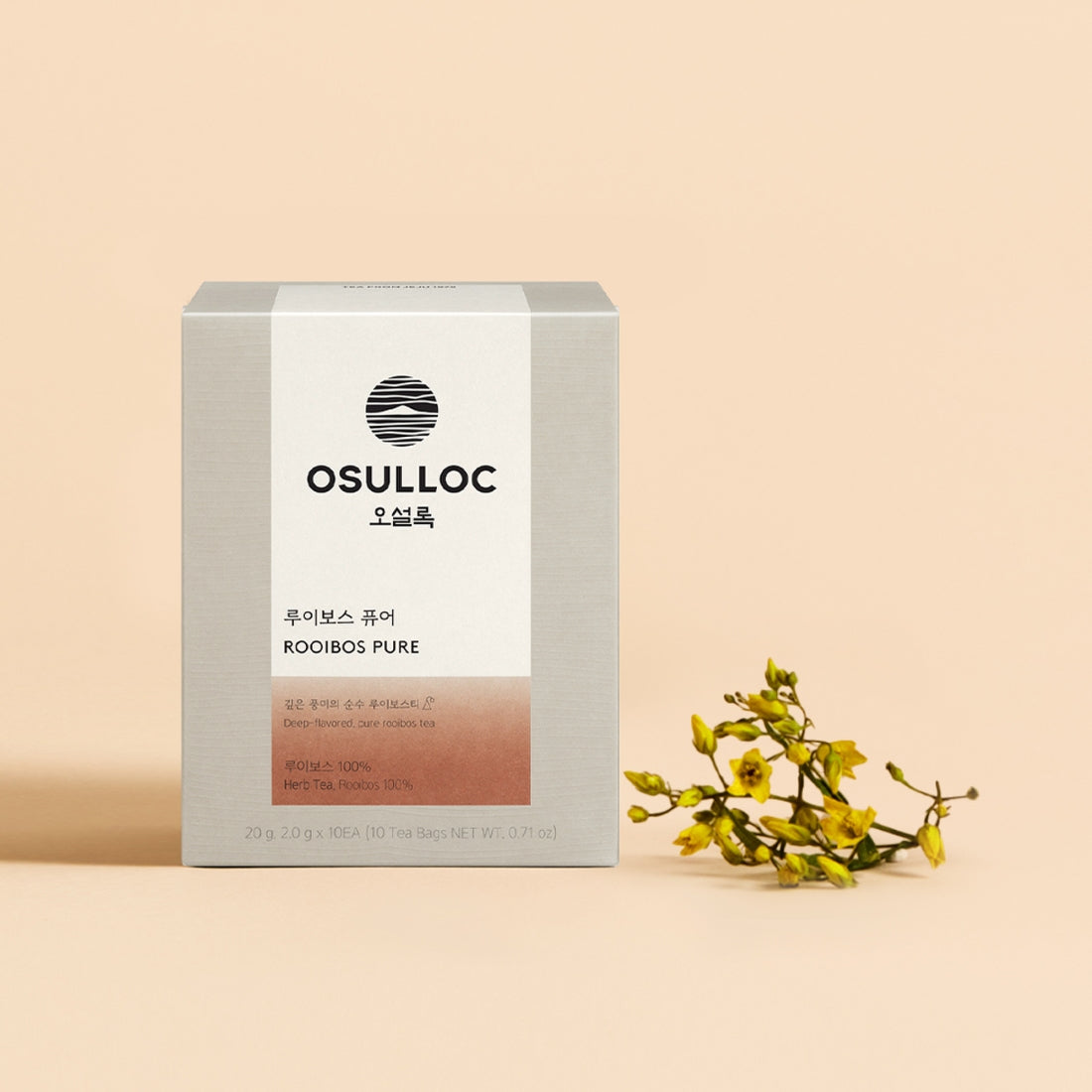 Boîte grise Rooibos Pure OSULLOC avec un verre d'infusion ambrée et fleurs jaunes décoratives.