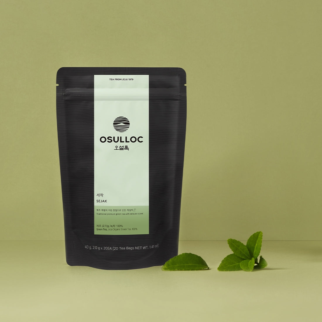 Sachet noir OSULLOC Sejack Green Tea avec une tasse de thé vert et des feuilles sèches en décoration.