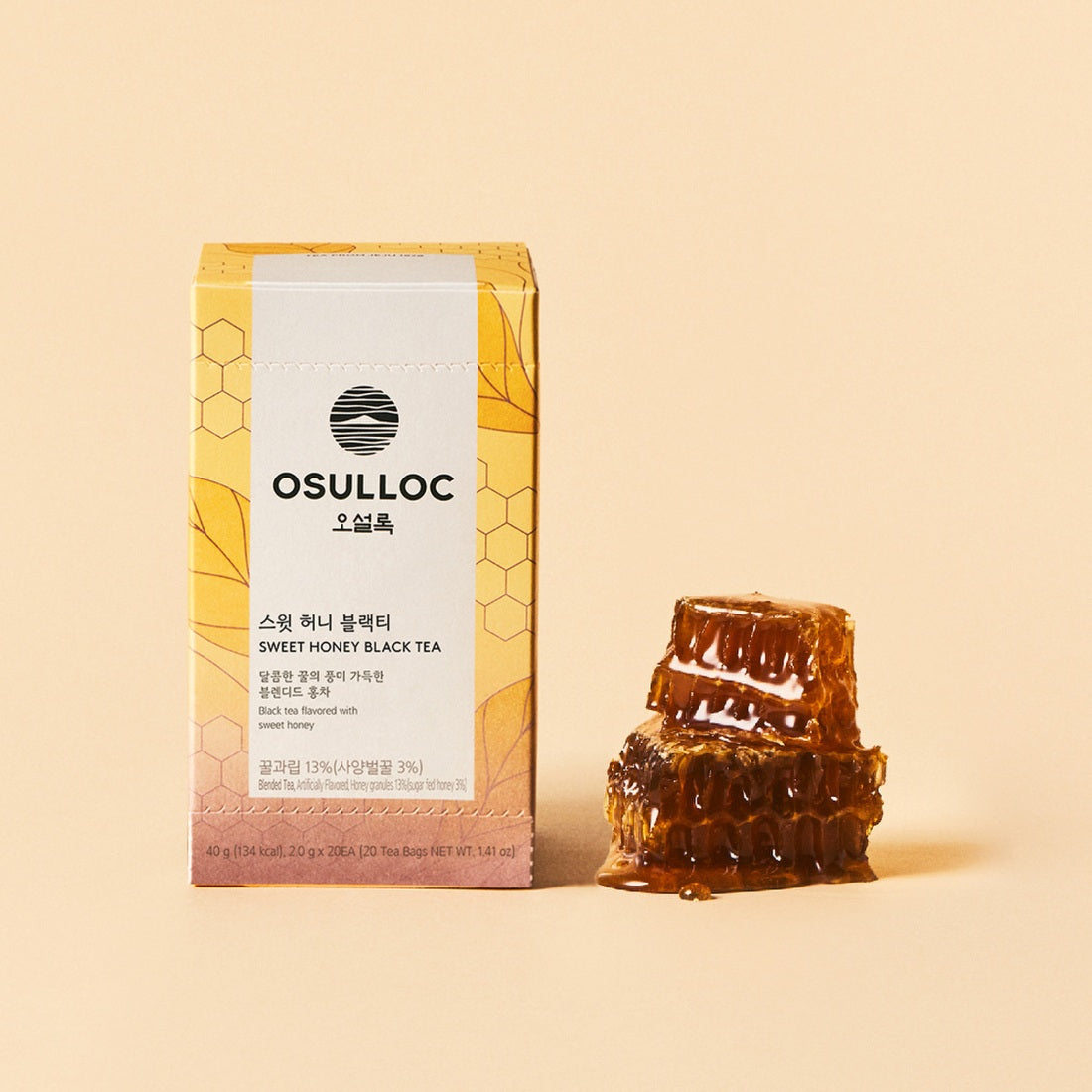 Boîte jaune pâle OSULLOC Sweet Honey Black Tea à côté d'un rayon de miel frais 