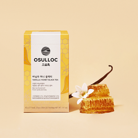 Boîte jaune OSULLOC Vanilla Honey Black Tea posée à côté de gousses de vanille, de fleurs blanches et d'un rayon de miel.