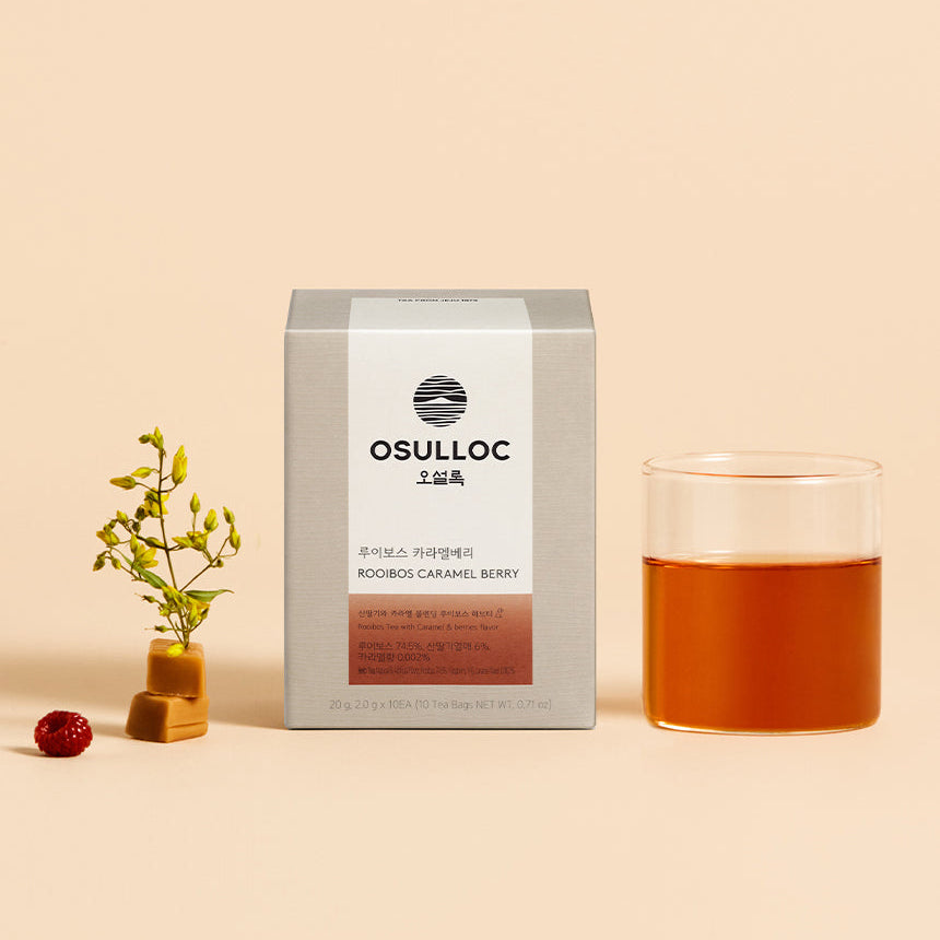 Boîte de Rooibos Caramel Berry OSULLOC beige avec une tasse d'infusion ambrée et des baies rouges.