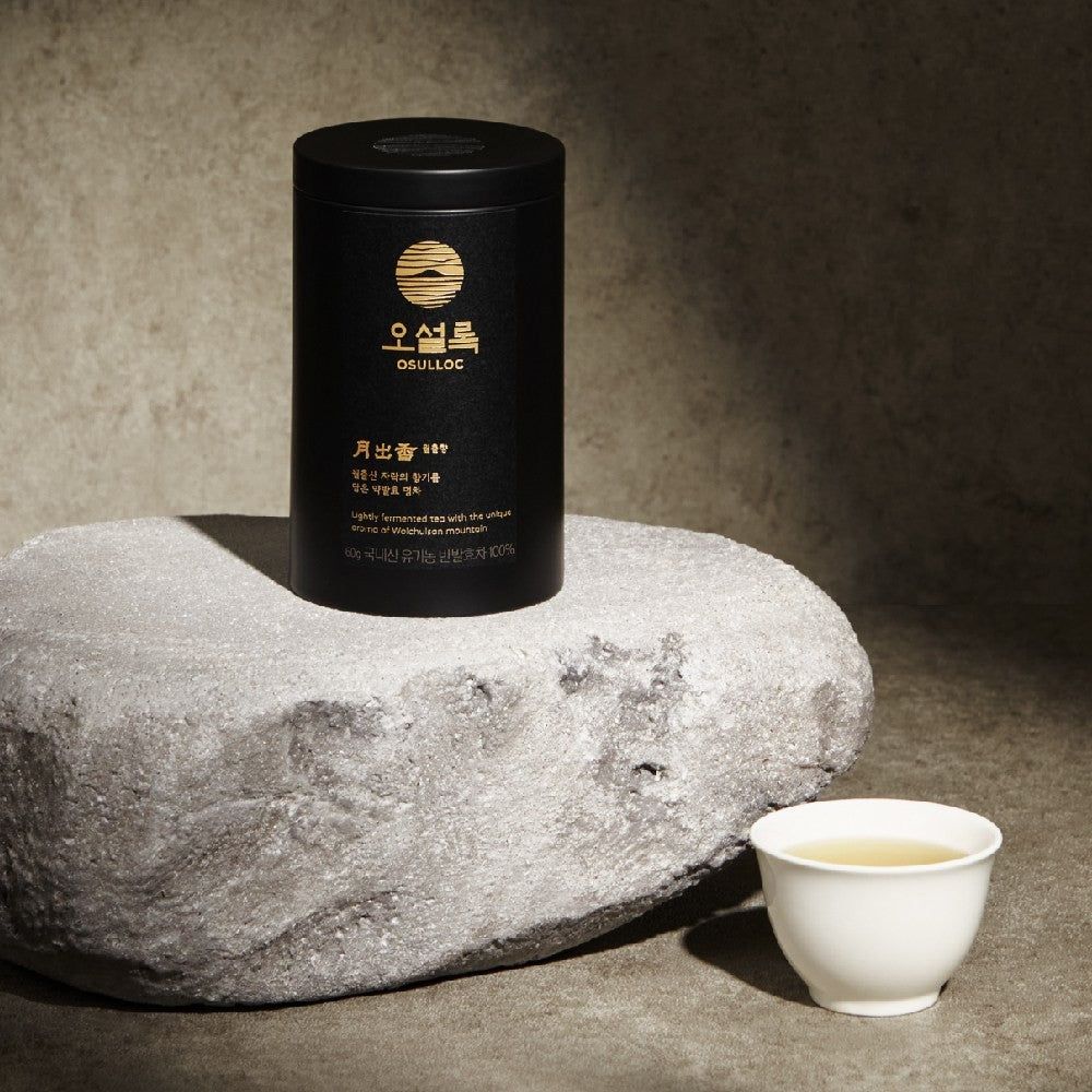 Boîte OSULLOC Wolchulhyang posée sur une pierre à côté d'une tasse de thé